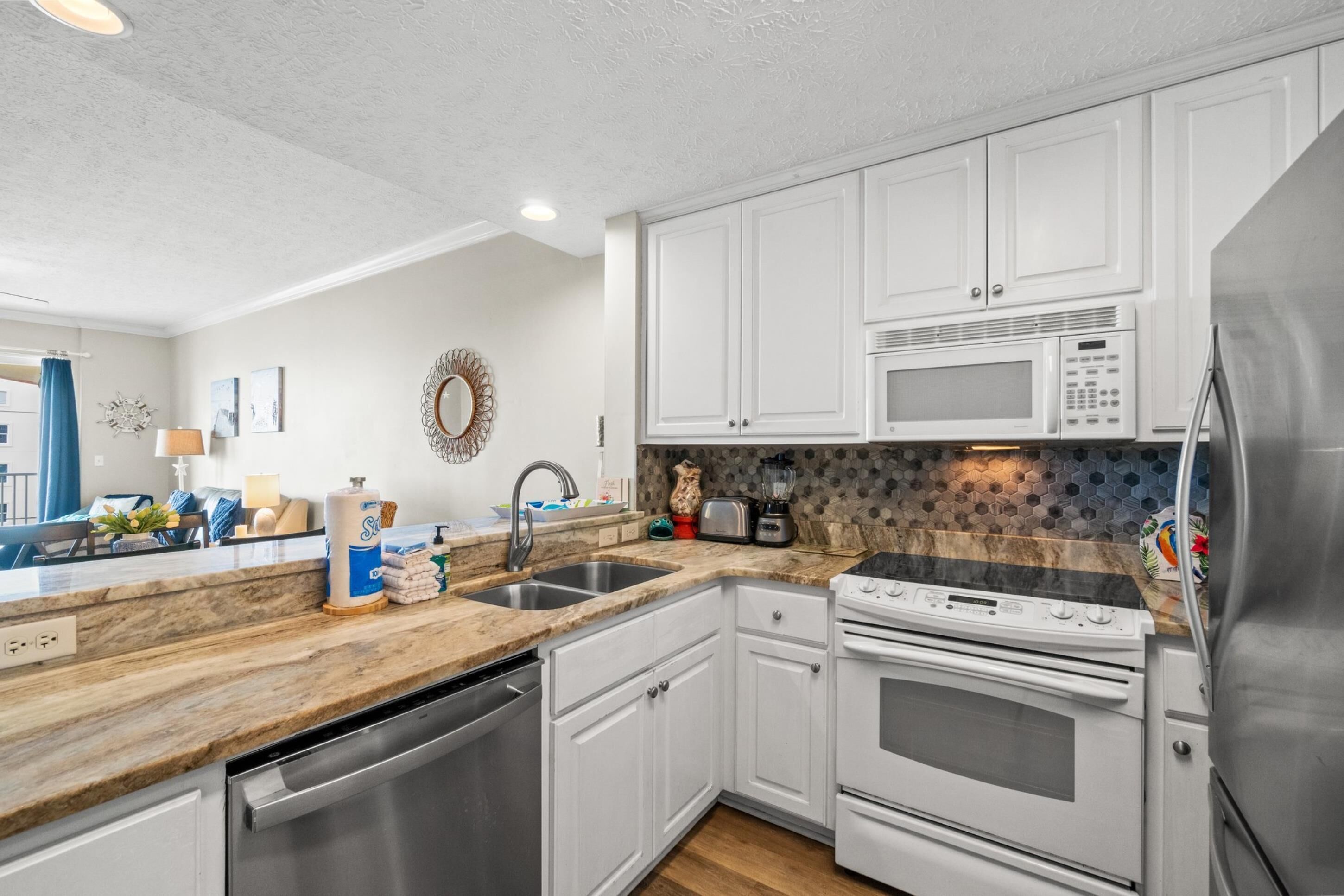A modern kitchen with white cabinets, stainless steel appliances, and a granite countertop.