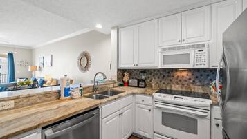 A modern kitchen with white cabinets, stainless steel appliances, and a granite countertop.