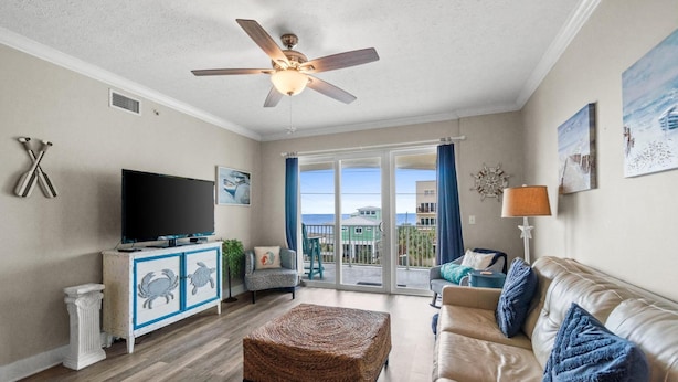 A living room with a television, sofa, ottoman, and a ceiling fan. - Mexico Beach - Summerhouse by PHG (Port St. Joe)