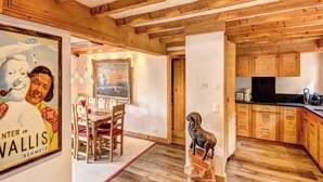A wooden interior with a dining area, kitchen, and a framed picture. - Luxurious Alpine Retreat in Verbier Place Centrale with Panoramic Mountain Views (Val de Bagnes)