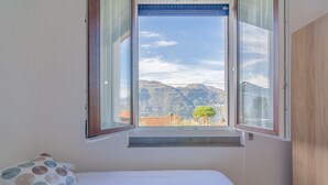 Una camera da letto con un letto, una finestra vista montagne e un armadio in legno.