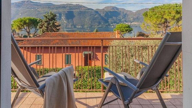 Un balcone con due sedie e vista su una montagna e un lago.