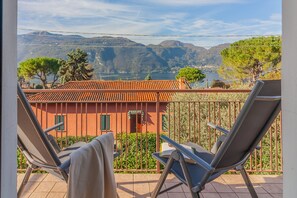Ein Balkon mit zwei Stühlen und Blick auf einen Berg und See.
