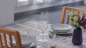 Un tavolo da pranzo apparecchiato con piatti, bicchieri e un vaso con fiori.