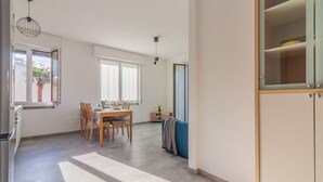 Un'ampia zona giorno con tavolo e sedie da pranzo, un divano e un angolo cottura con frigorifero.
