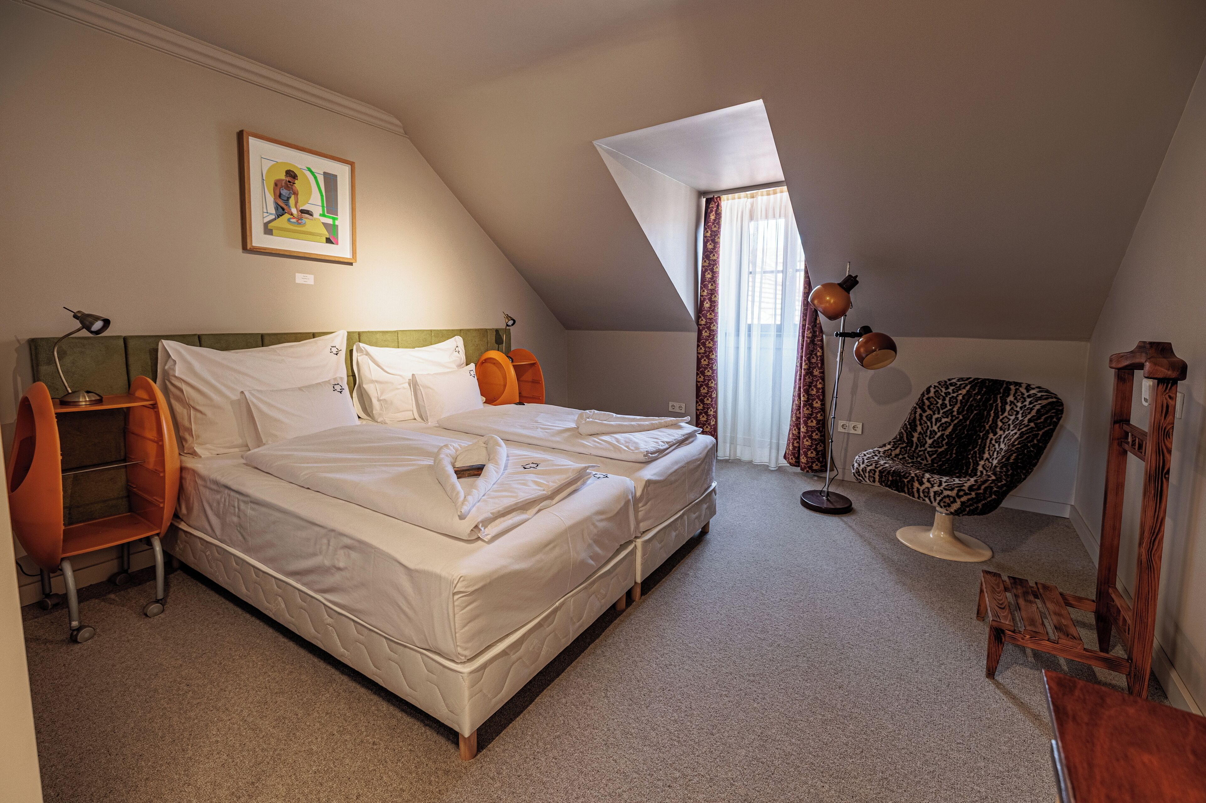 A bedroom with a bed, a chair, a desk, and a painting on the wall.