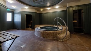 Un área de spa con un hidromasaje circular, un banco de madera y un techo con diseño circular.