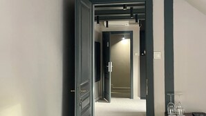 Un pasillo con techo inclinado, una puerta que da a otra habitación y una pequeña mesa con vasos.