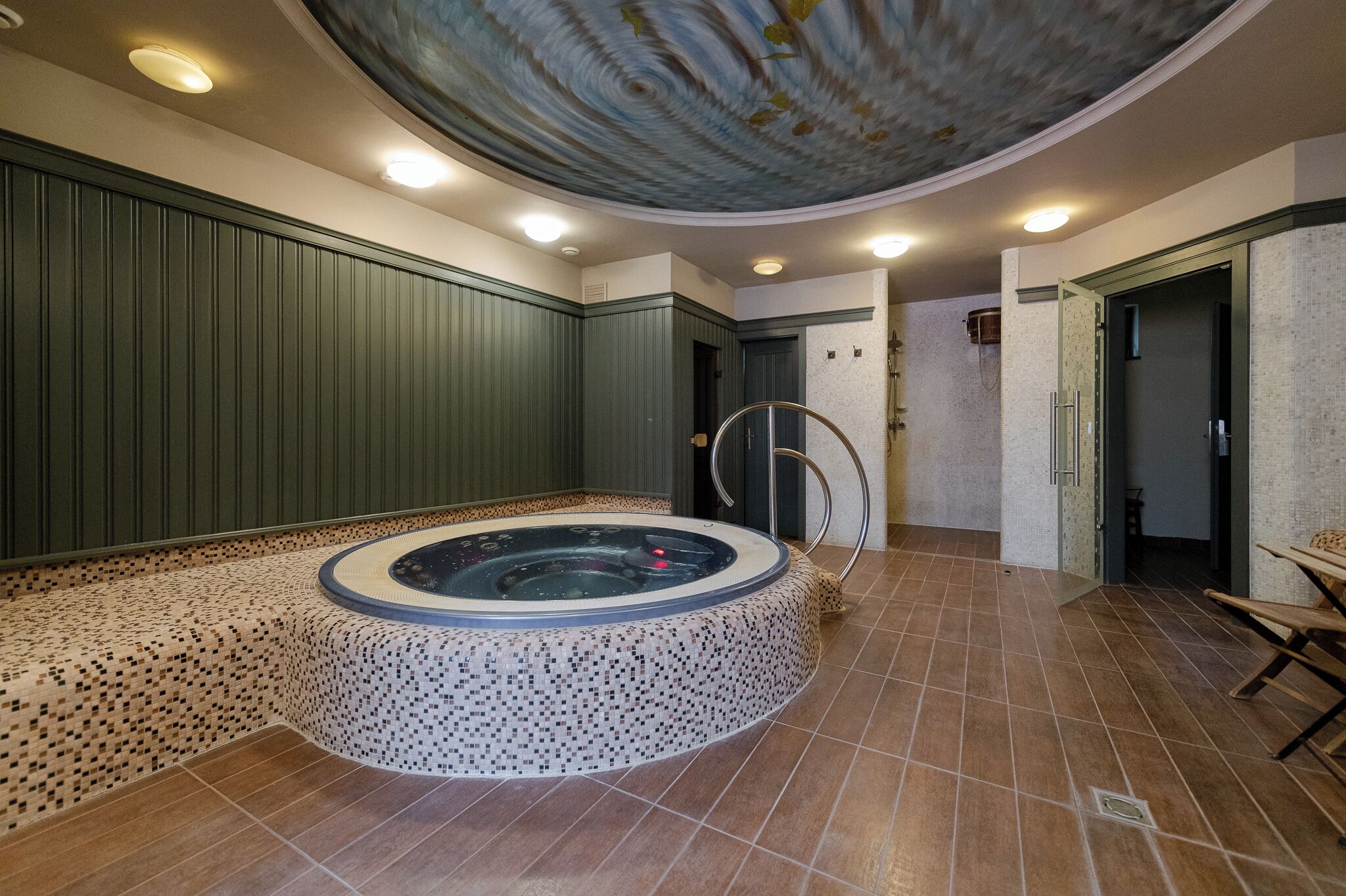 Un área de spa con una bañera de hidromasaje, suelo de baldosas y paneles de madera.