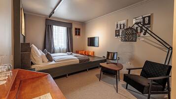 A modern hotel room with a bed, a desk, a chair, and artwork on the walls.