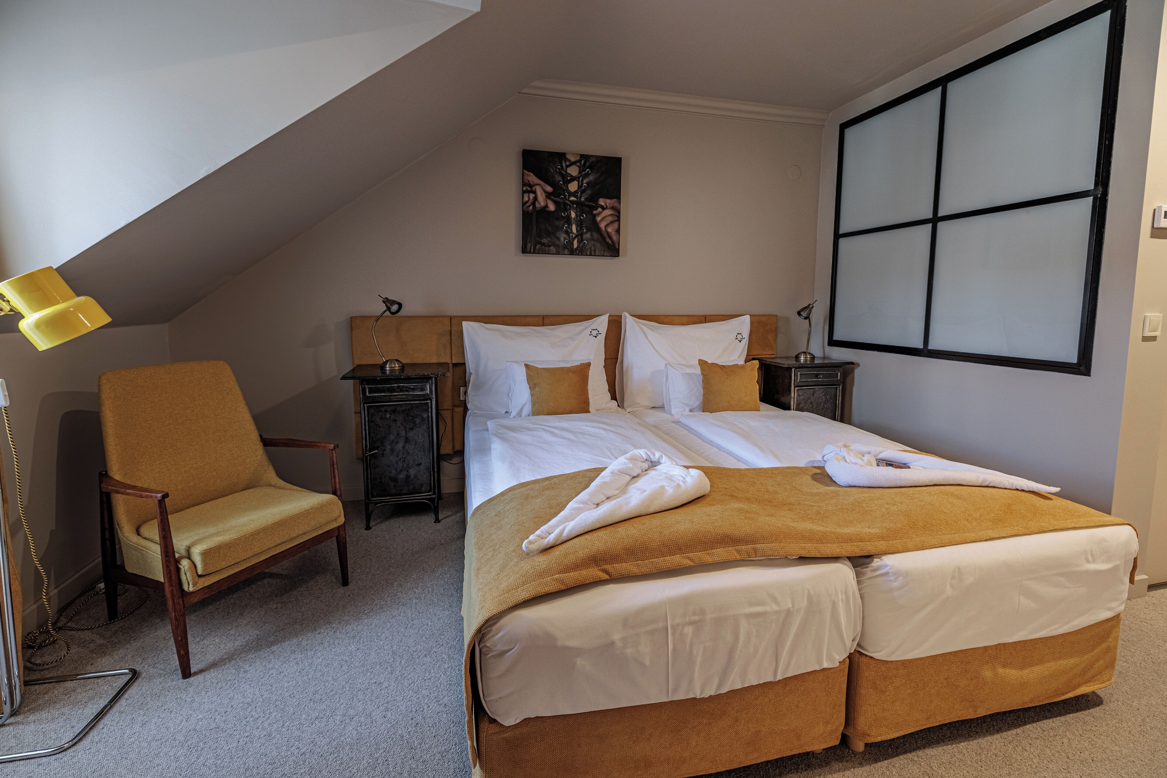 Une chambre d’hôtel avec un grand lit, une chaise, un bureau et un tableau au mur.