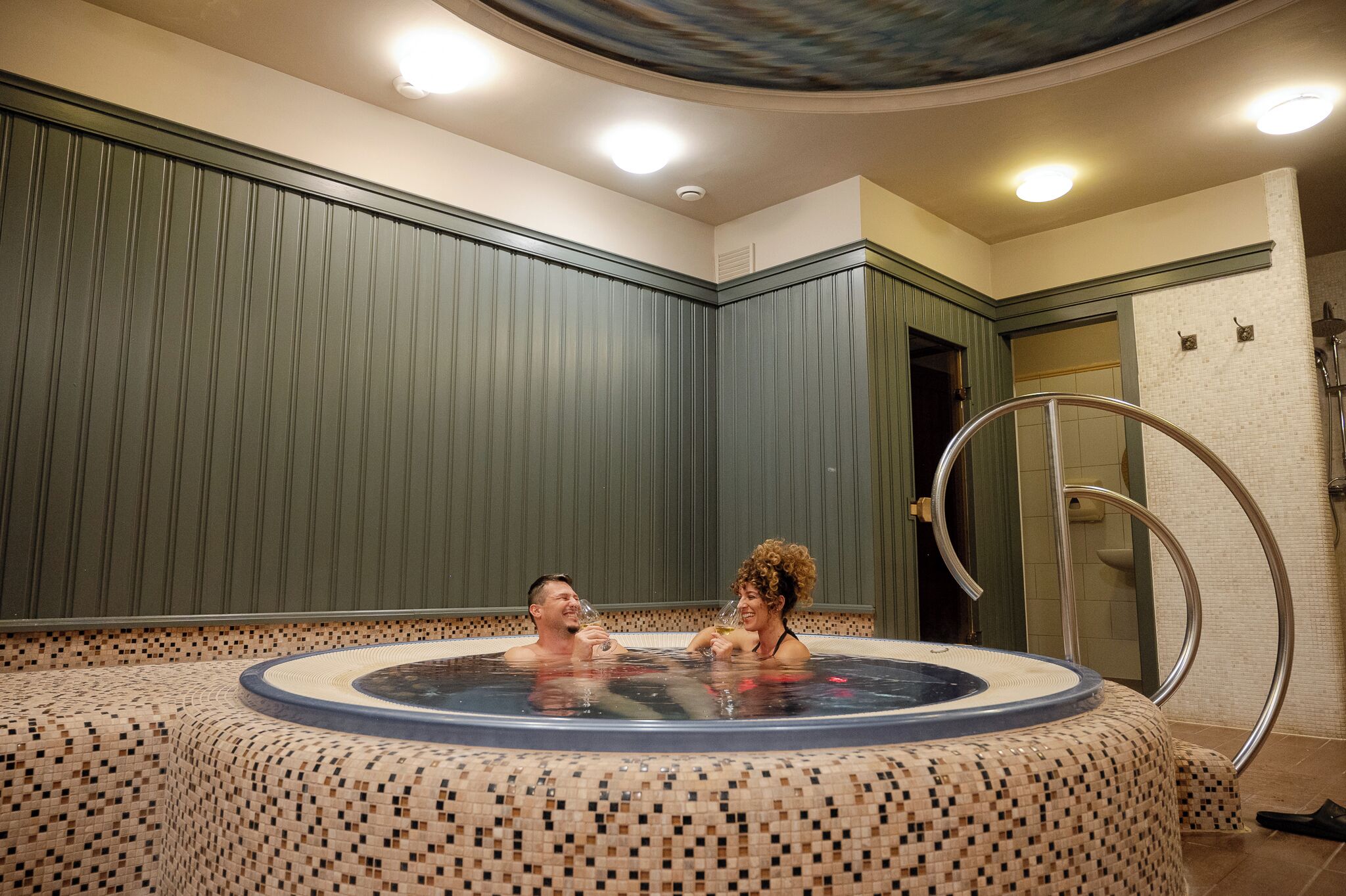 Un jacuzzi con piso de azulejos y baranda de metal.