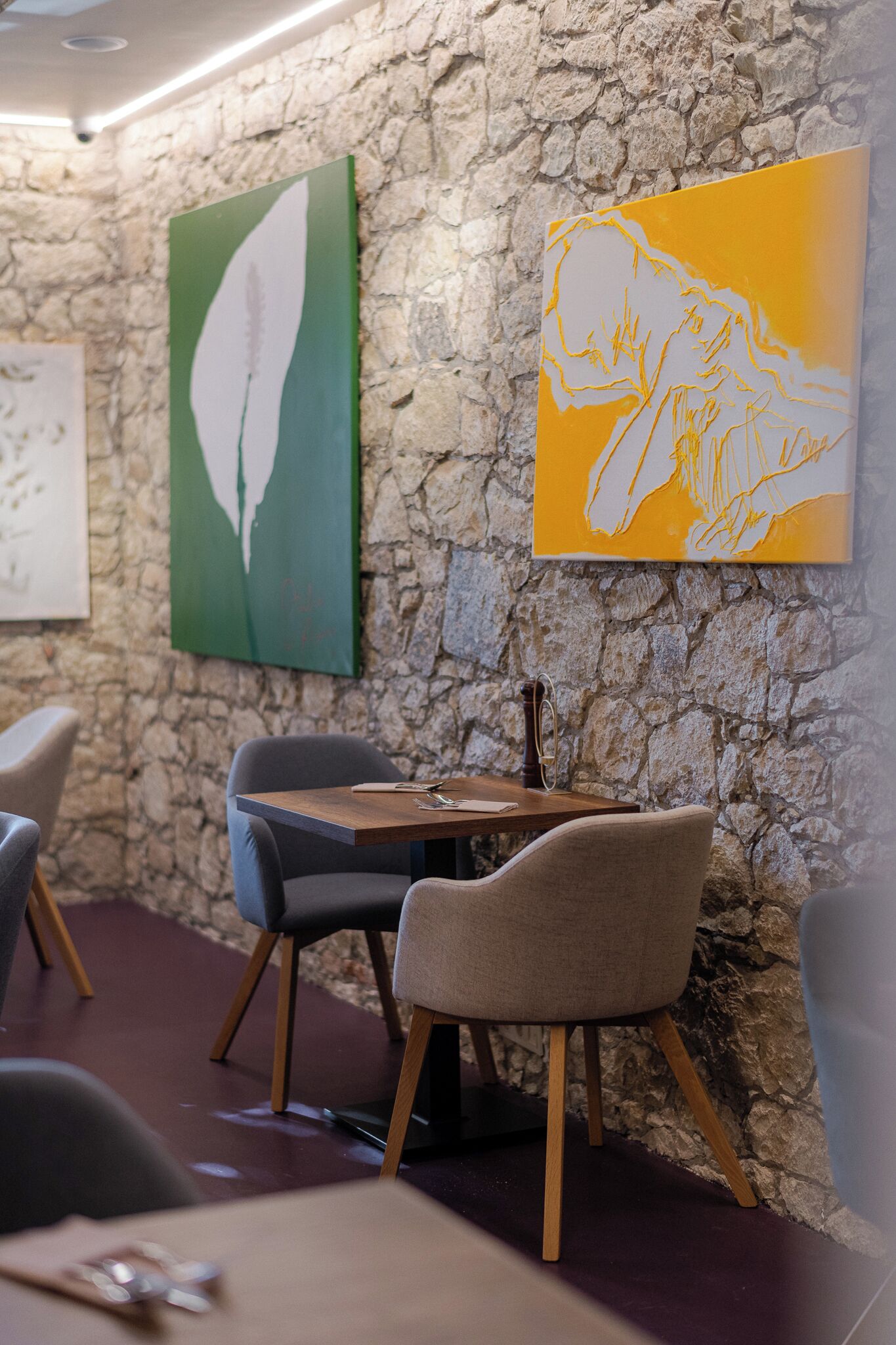 Interior de un restaurante con paredes de piedra, dos mesas y sillas.