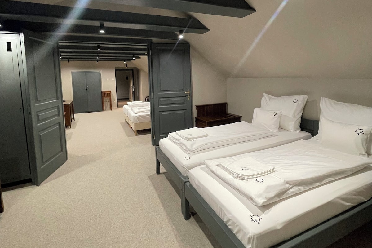 A bedroom with two beds, a wardrobe, and a door leading to another room.