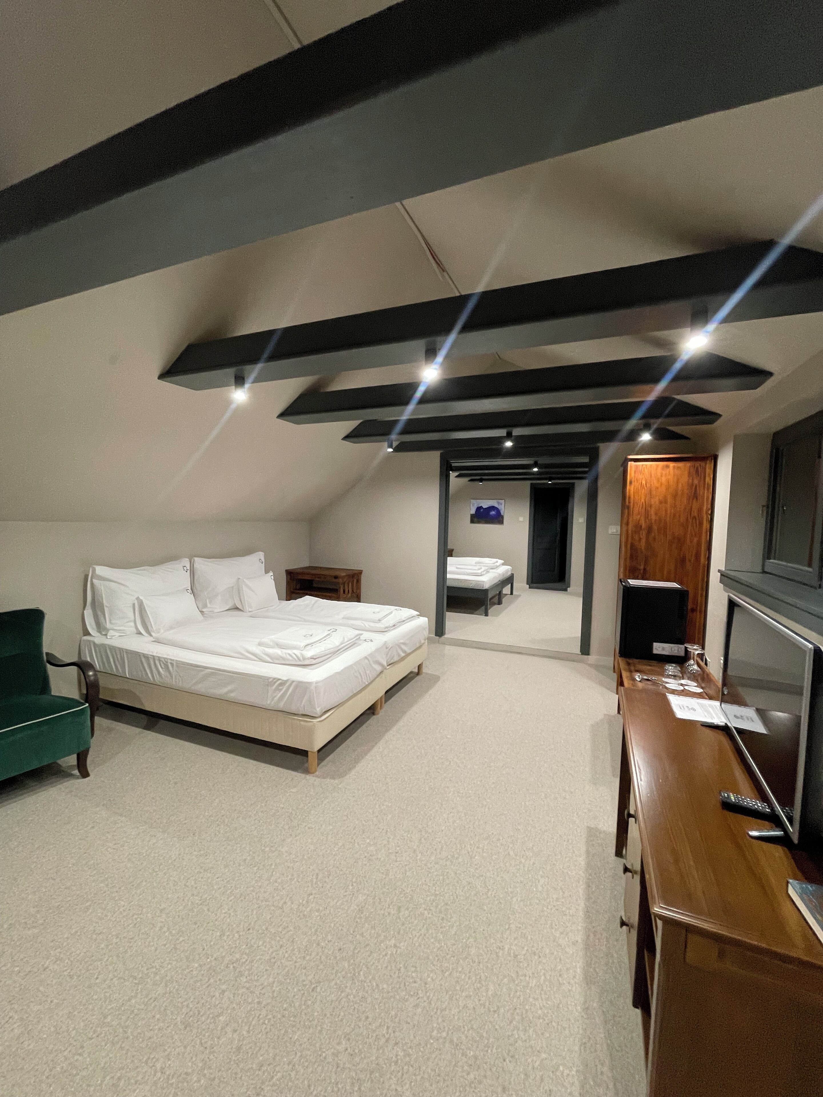 A modern hotel room with a large bed, a desk, and a television.