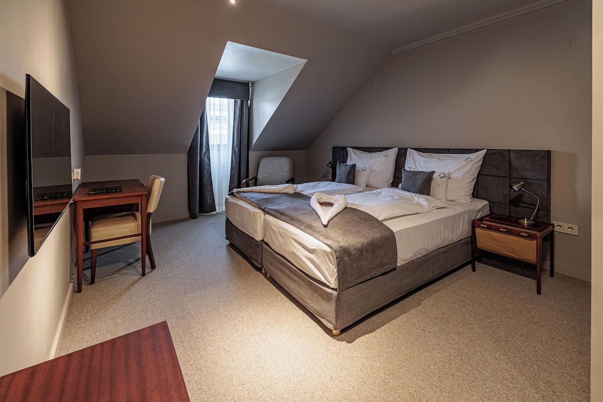 A bedroom with a bed, a desk, a chair, and a TV.