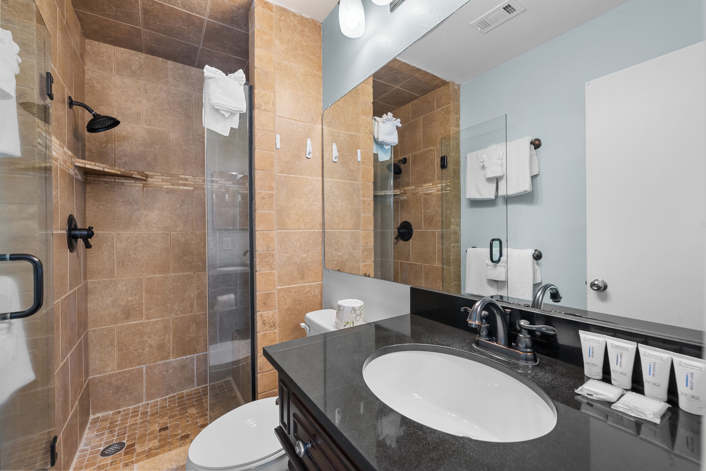 A modern bathroom with a glass-enclosed shower, a large sink, and a mirror.