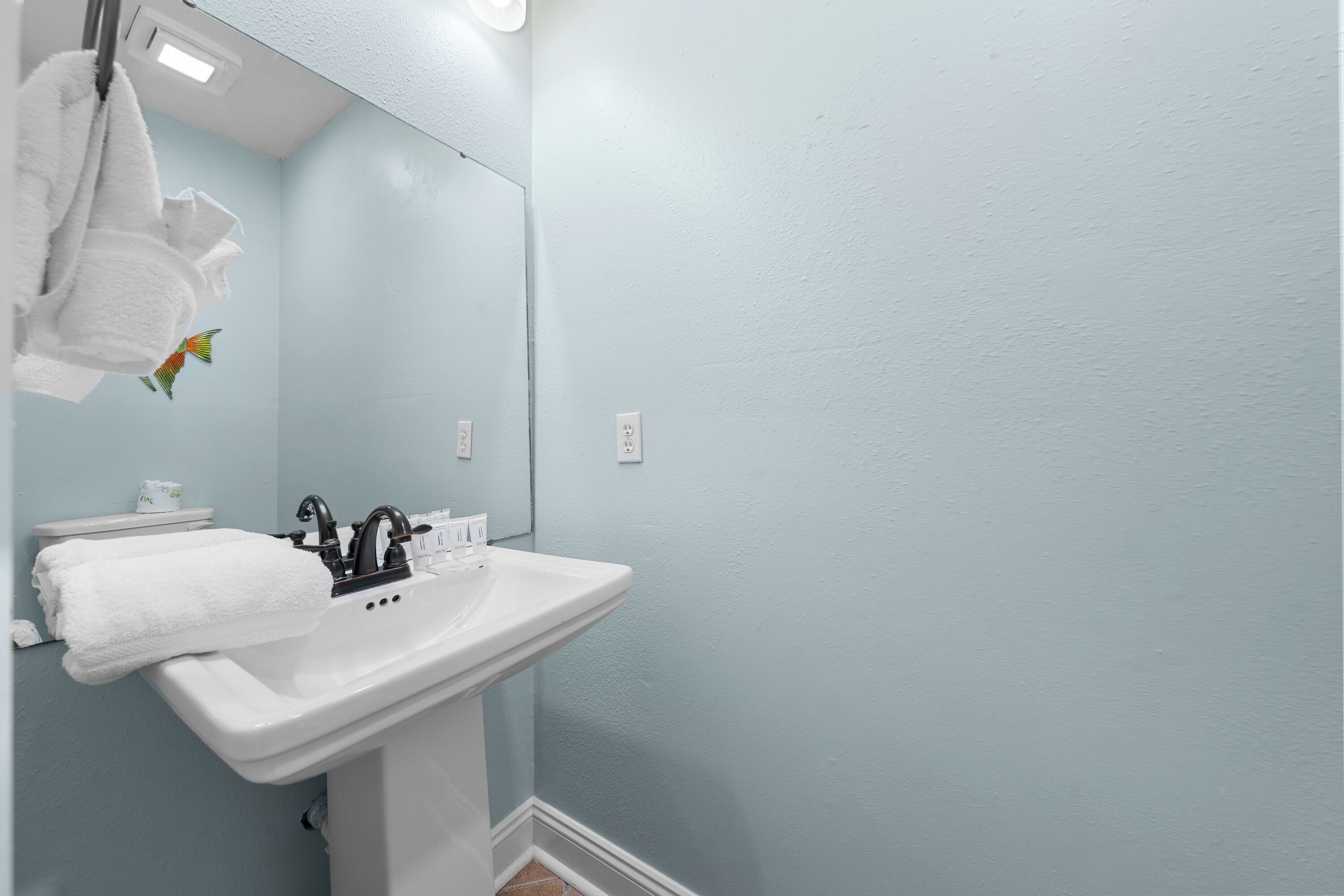 A bathroom with a white sink, a mirror, and a towel hanging on the wall.