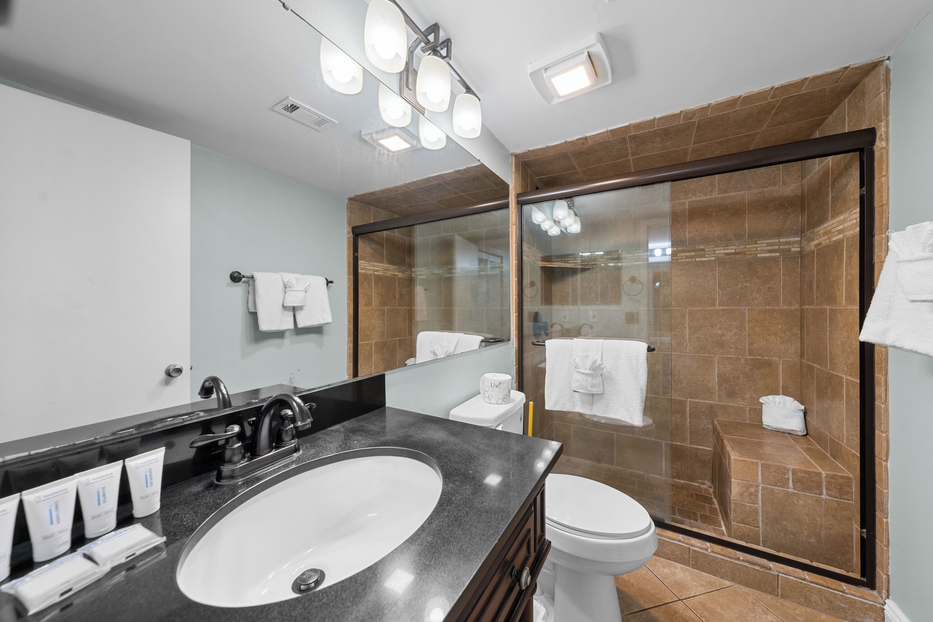 Un baño moderno con un lavamanos grande, inodoro y ducha con mampara de vidrio.
