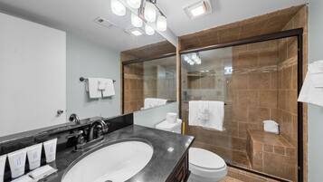 Un baño moderno con un lavamanos grande, inodoro y ducha con mampara de vidrio.