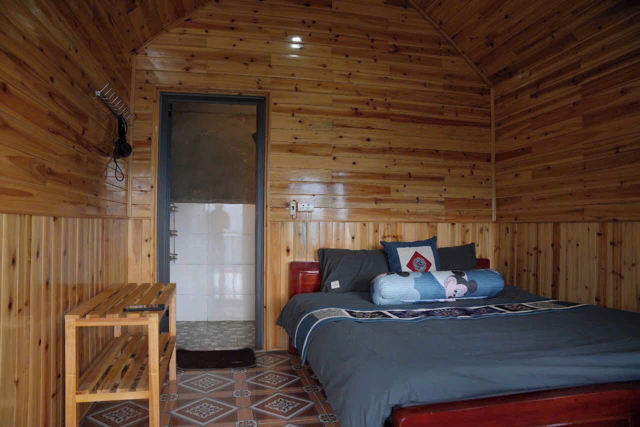 Una habitación con paneles de madera, una cama, un banco de madera y una puerta.