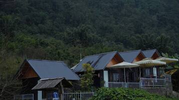 A row of cabins with metal roofs and wooden exteriors, surrounded by dense forest.