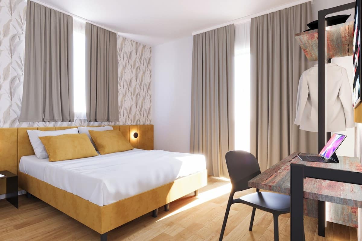 Ein modernes Hotelzimmer mit einem hölzernen Bett, einem Schreibtisch mit einem Laptop und einem Sessel.