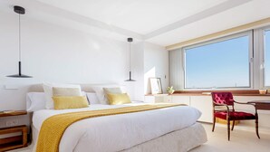 Un dormitorio moderno con una cama grande, mesitas de noche, un escritorio y una silla.