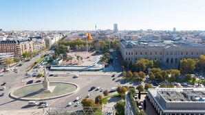 Un paisaje urbano con una rotonda destacada, un monumento y un edificio grande con arquitectura clásica.