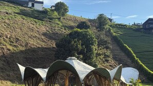 A modern architectural structure with a unique roof design, set against a backdrop of a hillside and a clear sky. - CasaMarella Exclusivity+HouseBoutique+Hydromassage

 (Morelia Pereira)