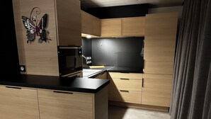 Una cocina moderna con armarios de madera, encimera negra y microondas.