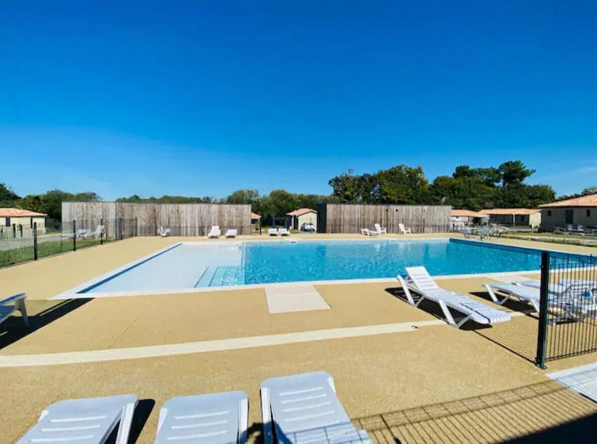A rectangular swimming pool with lounge chairs and a fenced area.