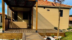 Una terraza de madera que da a un porche cubierto con una silla de mimbre.