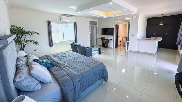 Een moderne hotelkamer met een groot bed, een bureau, een televisie en een kitchenette.