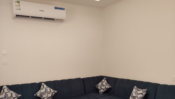 Uma sala de estar moderna com um sofá seccional azul escuro, uma mesa de centro redonda e tapetes estampados.