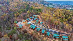 A lodge with multiple cabins, surrounded by a forested hillside. - Tennessee Time is always right (PIGEON FORGE)