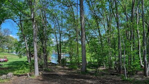 A forested area with a wooden deck in the foreground. - Red Roof Retreat at Lake Anna, Waterfront w/kayaks, fire pit, grill & large deck (Bumpass)