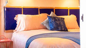 Una cama con cabecera, almohadas y una colcha.