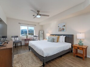 Relax in this serene bedroom with a large bed, nightstands, and a ceiling fan, offering a peaceful view of the surrounding mountains.