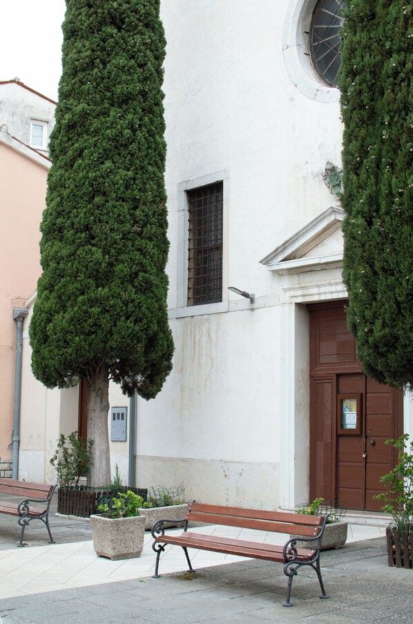 Un banc devant un bâtiment doté d’une fenêtre ronde et d’une porte.