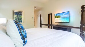 Une chambre d’hôtel avec un lit, un téléviseur fixé au mur et un tableau encadré.