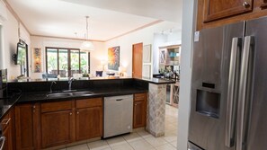 A modern kitchen with a Bosch refrigerator, wooden cabinets, a dishwasher, and a large window providing natural light. - Elegant 3 BR Ground-Floor Apartment with Hot Tub (Cocle)
