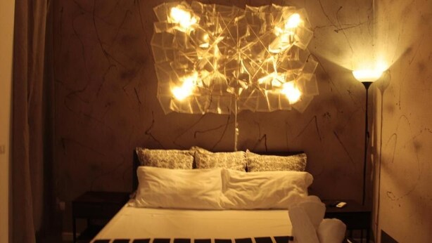 A bedroom with a bed, pillows, a bedside table, and a wall-mounted light fixture. - Large apartment in the city center with terrace and two kitchens. (Catania)