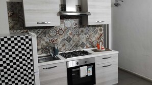 A compact kitchen with a gas stove, a built-in oven, a sink, and a microwave. - Large apartment in the city center with terrace and two kitchens. (Catania)