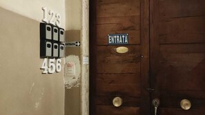 A wooden door with a sign reading "ENTRATA" and a plaque above it. There are two keys hanging on the wall to the left. - Large apartment in the city center with terrace and two kitchens. (Catania)
