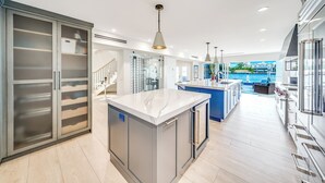 A modern kitchen with a marble island, stainless steel appliances, and a view of the city. - Waterfront Gem! Heated Pool+HotTub! Close 2 Beach! (Pompano Beach)