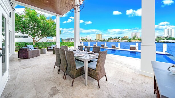An outdoor patio with a dining table and chairs, overlooking a swimming pool and city skyline. - Waterfront Gem! Heated Pool+HotTub! Close 2 Beach! (Pompano Beach)