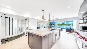A modern kitchen with a large island, pendant lighting, and a view of the water. - Waterfront Gem! Heated Pool+HotTub! Close 2 Beach! (Pompano Beach)