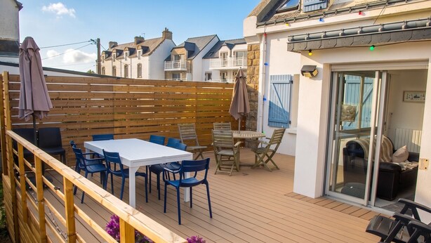 A wooden deck with a table and chairs, a glass door entrance, and a wooden fence. - 3 *** village house, bright veranda opening onto terrace and large garden (Quiberon)