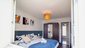 A bedroom with a bed, a nightstand, a mirror, and a door leading to another room. - 3 *** village house, bright veranda opening onto terrace and large garden (Quiberon)